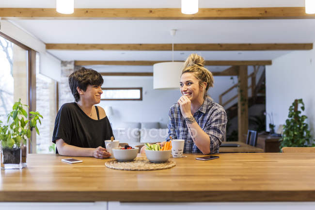 Duas mulheres bonitas e jovens tomando café da manhã em casa e se divertindo — Fotografia de Stock