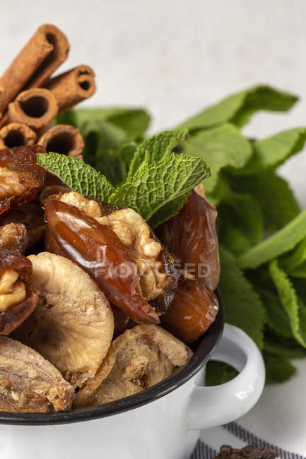 Closeup of dried dates, figs, fresh mint and cinnamon for halal snack for Ramadan in pot — Stock Photo