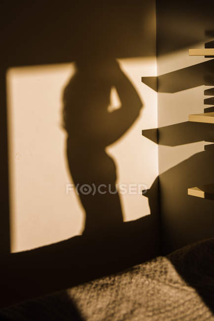 Тінь жінки, спроектована на стіні біля ліжка — стокове фото