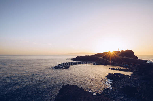 À beira-mar rochoso remoto ao pôr do sol brilhante — Fotografia de Stock