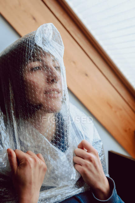Mulher assustada tentando se libertar enquanto enredada em plástico bolha — Fotografia de Stock