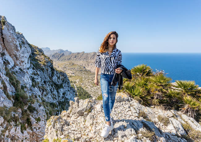 Молода жінка стоїть на скелі — стокове фото