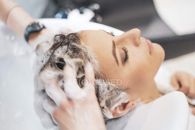 Стиліст миє волосся молодій леді — стокове фото