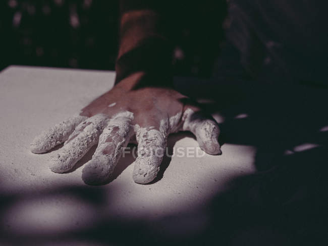 Рука анонімного художника-чоловіка, що розкладає грубу білу штукатурку на звичайній поверхні в майстерні — стокове фото