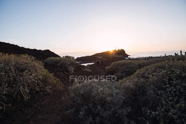 Чоловічий фотограф, що йде на узбережжі на заході сонця — стокове фото