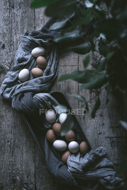 Chicken eggs on tablecloth on rustic wooden table — Stock Photo
