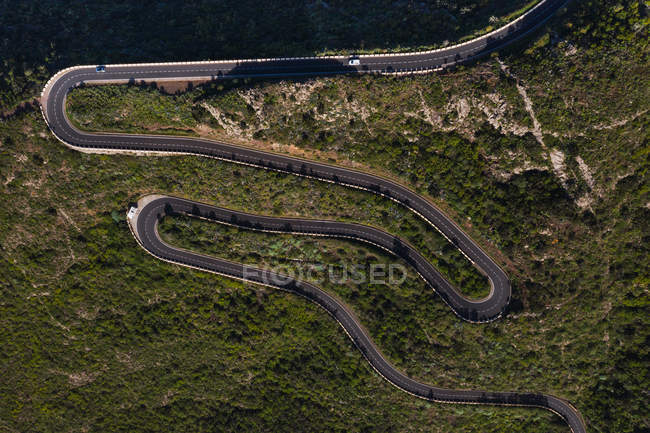 Luftaufnahme einer leeren kurvenreichen Landstraße in grüner, abgelegener sonniger Landschaft Spaniens — Stockfoto