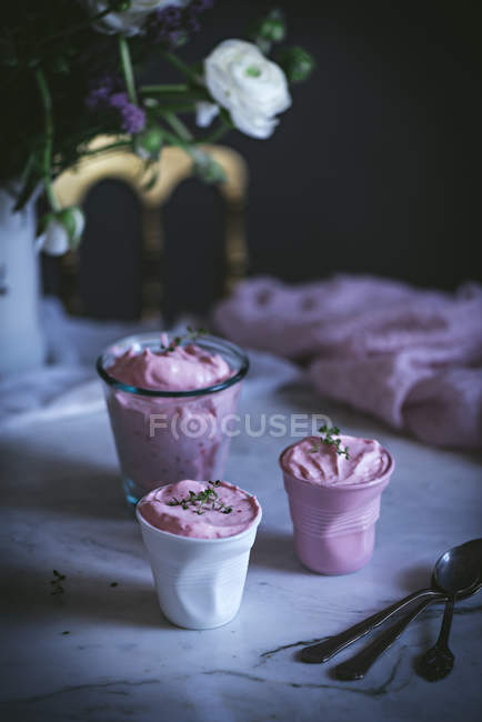 Glasses of sweet strawberry mousse on table with flowers — Stock Photo