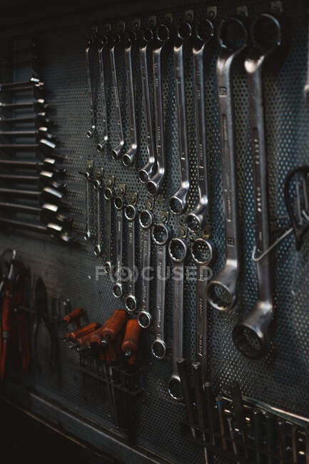 Set of assorted repair tools attached to grungy metal wall in professional workshop — Stock Photo