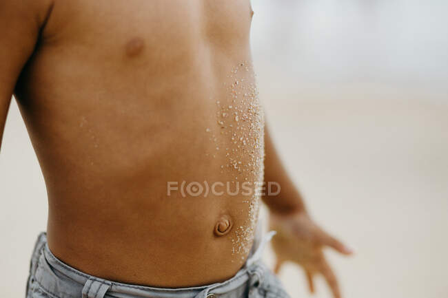 Bambino afroamericano irriconoscibile con sabbia sulla pancia che trascorre del tempo sulla spiaggia — Foto stock