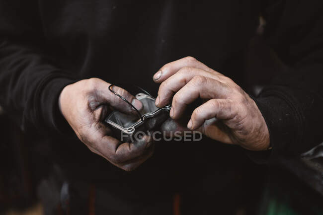 Unrecognizable repairman with dirty hands gluing broken part in workshop — Stock Photo
