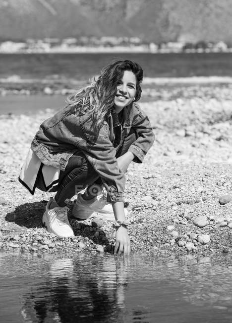 Молодая женщина играет с водой на берегу — стоковое фото