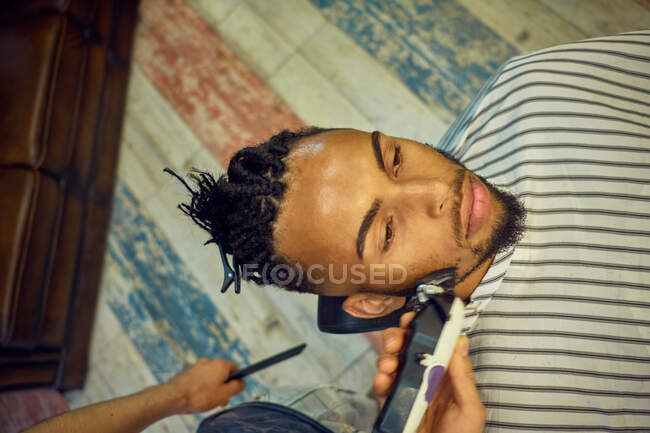 Vue du dessus d'un coiffeur anonyme toilettant un client afro-américain — Photo de stock