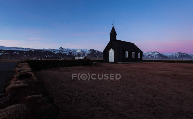 Paesaggio montano con chiesa cristiana in legno nero Budakirkja in Islanda — Foto stock