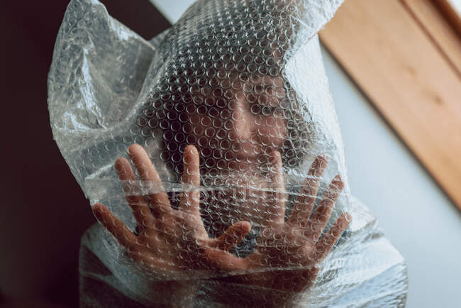 Mujer asustada tratando de liberarse mientras enredada en una envoltura de burbujas - foto de stock