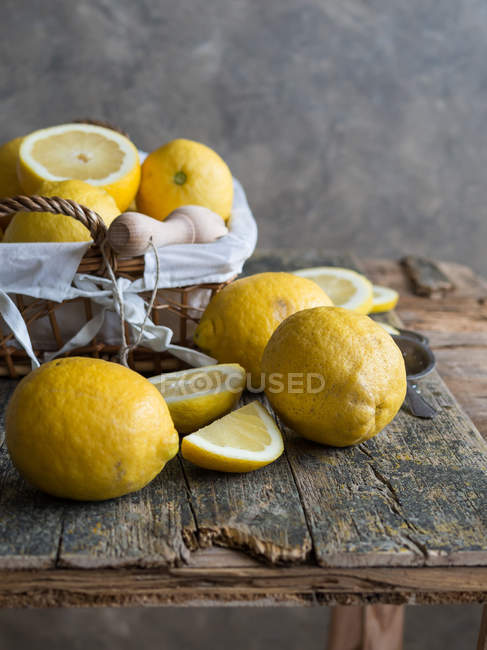 Limões frescos e espremedor de madeira na placa de madeira — Fotografia de Stock