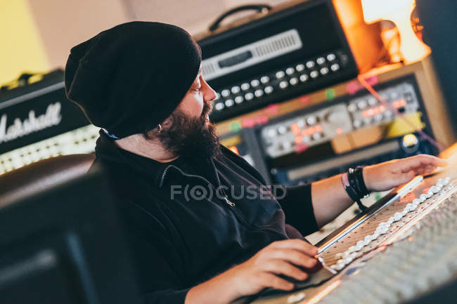 Músico trabajando mientras toca en un instrumento de ecualizador en un estudio - foto de stock