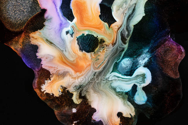 Spills of multicolored metallic dye mixing and spreading on black background — Stock Photo