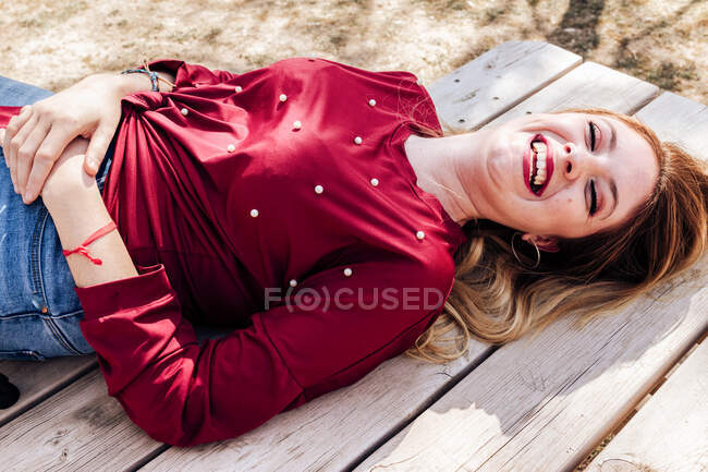 Donna sorridente sdraiata sul tavolo da picnic — Foto stock