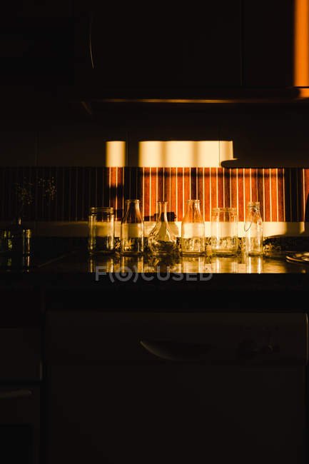 Empty glasses under dramatic light on cooktop of dark kitchen — Stock Photo