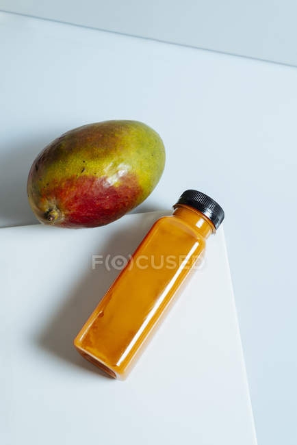 Frullato vegano al mango e zucca in bottiglia su fondo bianco con ingrediente — Foto stock