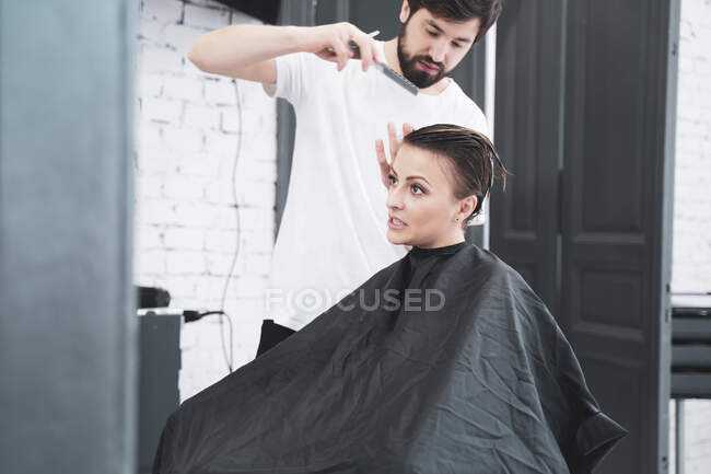 Coiffeur coupe les cheveux de la femme avec des ciseaux — Photo de stock