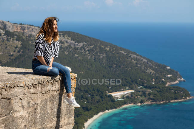 Женщина, сидящая на бетонном блоке у моря — стоковое фото