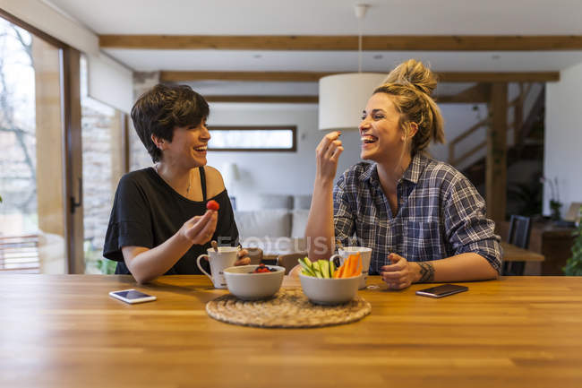 Two beautiful and young women having breakfast at home and having fun — Stock Photo