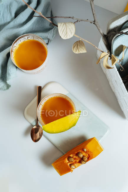Mango und Pumpsmoothie in Gläsern mit Zutaten auf weißem Hintergrund — Stockfoto