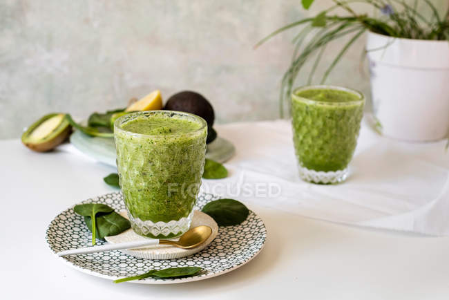 Smoothie verde saudável de espinafre, abacate e kiwi, maçã e limão em vidro no prato — Fotografia de Stock