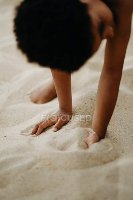 Funny African American boy playing on sandy shore near sea — Stock Photo