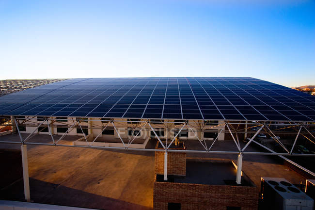 Будівля з дахом з сонячних панелей під блакитним небом — стокове фото