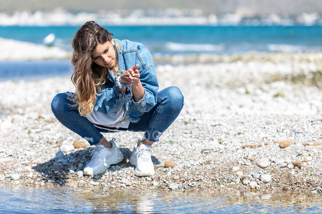 Молода жінка грає з водою на березі — стокове фото