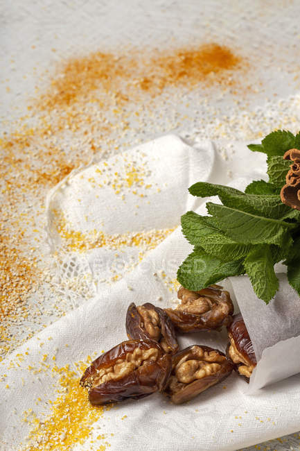 Halal snack for Ramadan with dried dates, figs, fresh mint and cinnamon on white cloth — Stock Photo
