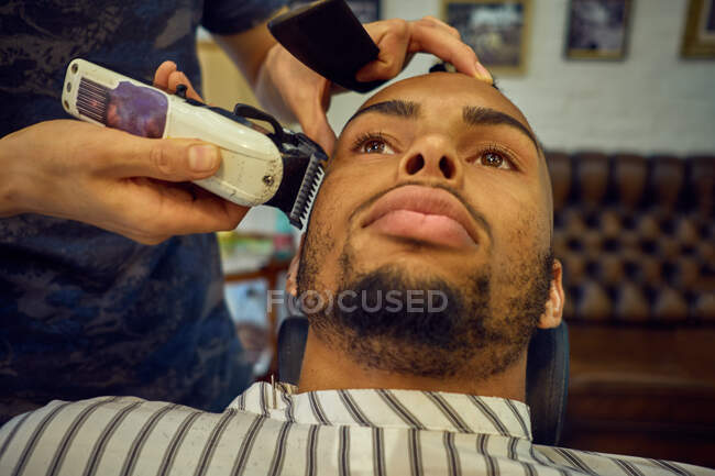 Vue rapprochée d'un coiffeur anonyme toilettant un client afro-américain — Photo de stock
