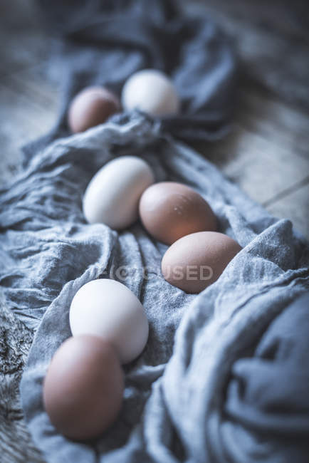 Ovos de galinha na toalha de mesa na mesa de madeira rústica — Fotografia de Stock