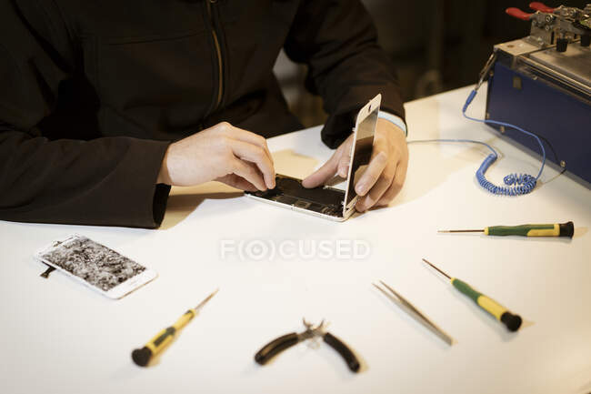 Молодой человек ремонтирует современное устройство — стоковое фото