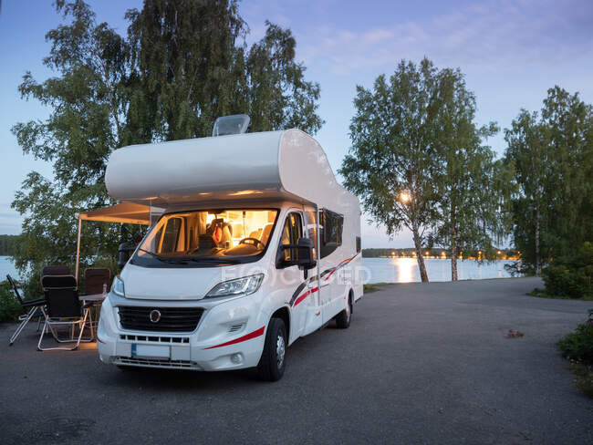 White stylish camper car parking for comfortable picnic near lake in summer evening — Stock Photo