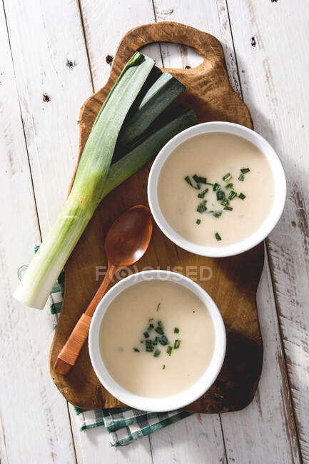 Shoot from above of two bowls of tasty Vichyssoise soups on wooden table with leek — Stock Photo