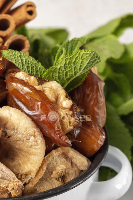 Gros plan de dattes séchées, figues, menthe fraîche et cannelle pour collation halal pour Ramadan en pot — Photo de stock