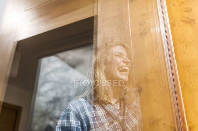 Reflexão bela e jovem mulher em uma janela de sua casa e sorrindo — Fotografia de Stock