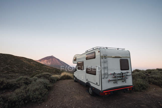 Caravana na beira da estrada na paisagem do deserto no fundo da montanha na luz do amanhecer — Fotografia de Stock