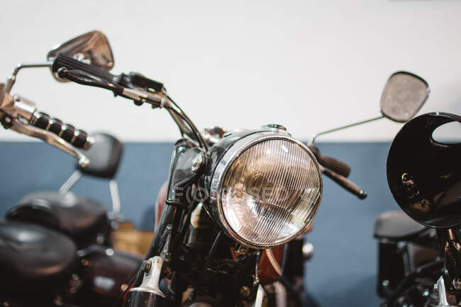 Shabby vintage motorbikes with broken headlights parked inside repair workshop — Stock Photo