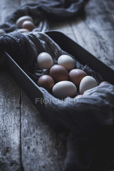 Hühnereier auf Tischdecke im Container auf rustikalem Holztisch — Stockfoto