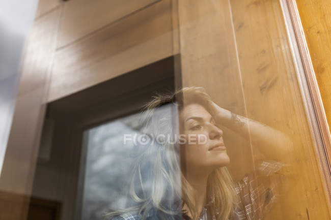 Beautiful and young woman reflection in a windows of her house and smiling — Stock Photo