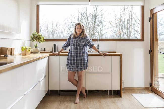 Schöne junge Frau in der Küche ihres Hauses und blickt in die Kamera — Stockfoto
