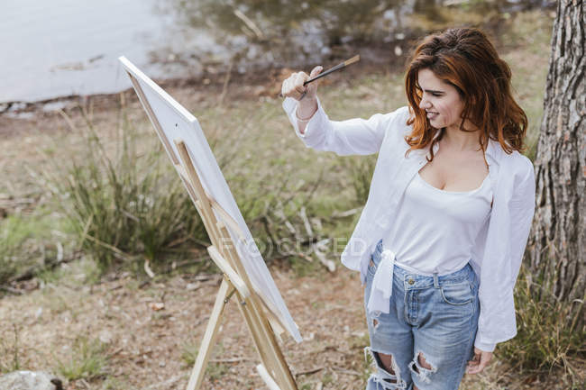Mujer joven pintando en el campo - foto de stock