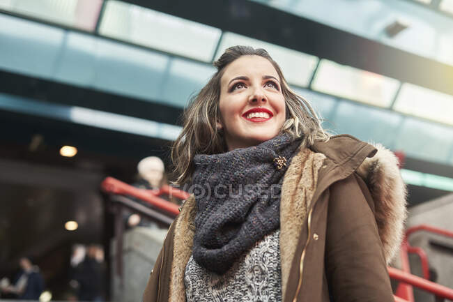 Портрет молодой веселой женщины, смотрящей в сторону транспортной станции — стоковое фото