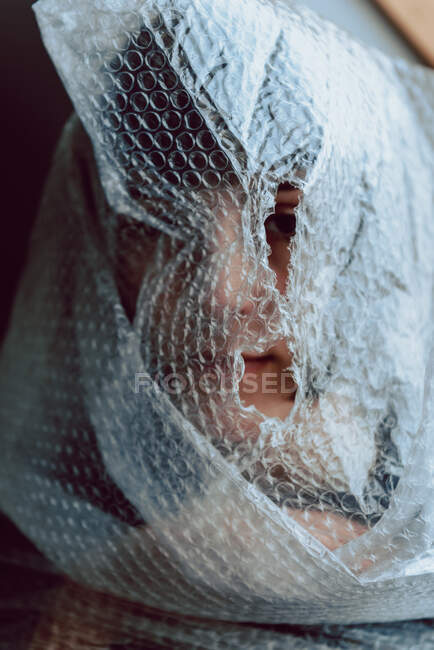 Женщина смотрит в камеру, запутавшись в пузырчатой пленке — стоковое фото