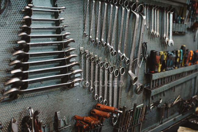 Conjunto de ferramentas de reparo sortidas anexado à parede de metal grungy na oficina profissional — Fotografia de Stock